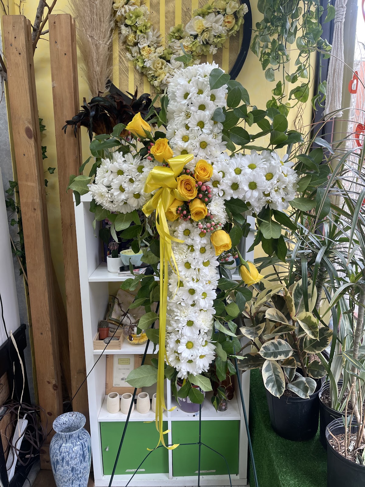 Funeral cross arrangement in white chrysanthemums with yellow rose centre