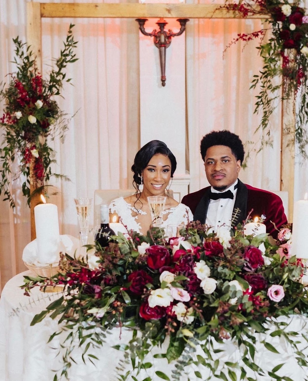 A Verdure wedding sweetheart table with burgundy floral installation